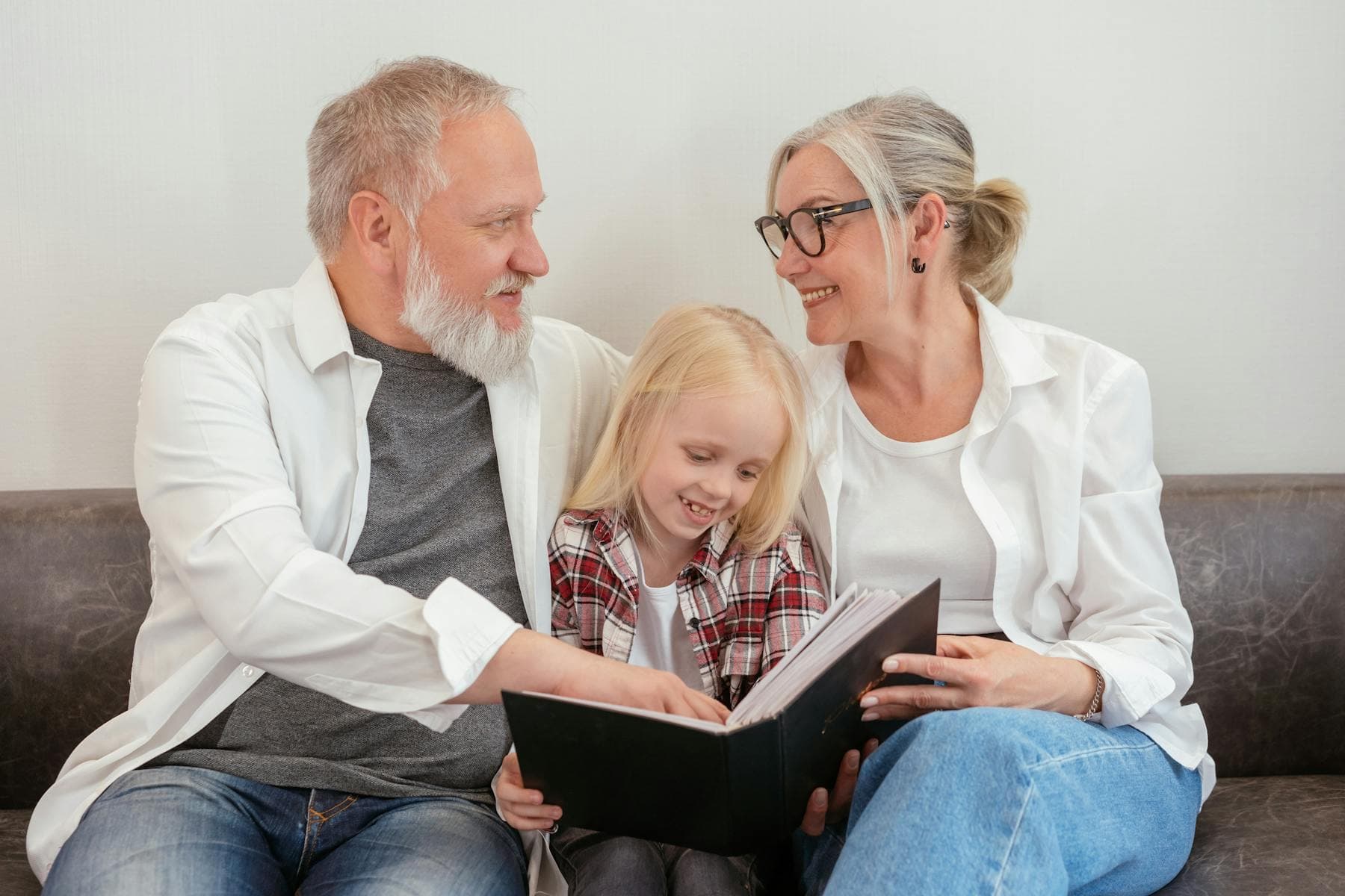 Grandparents and child looking at a photo album before starting a free private family tree online